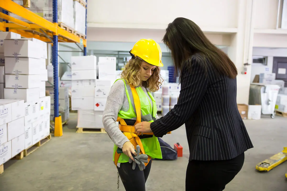 Woman helping worker with safety harness.