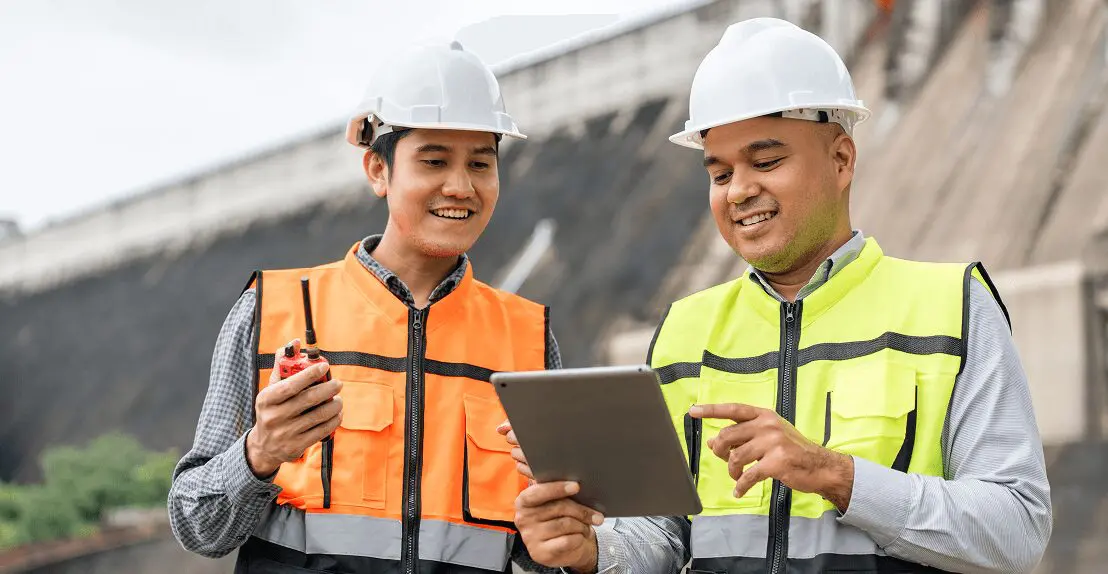 Engineers discussing project with tablet outdoors.