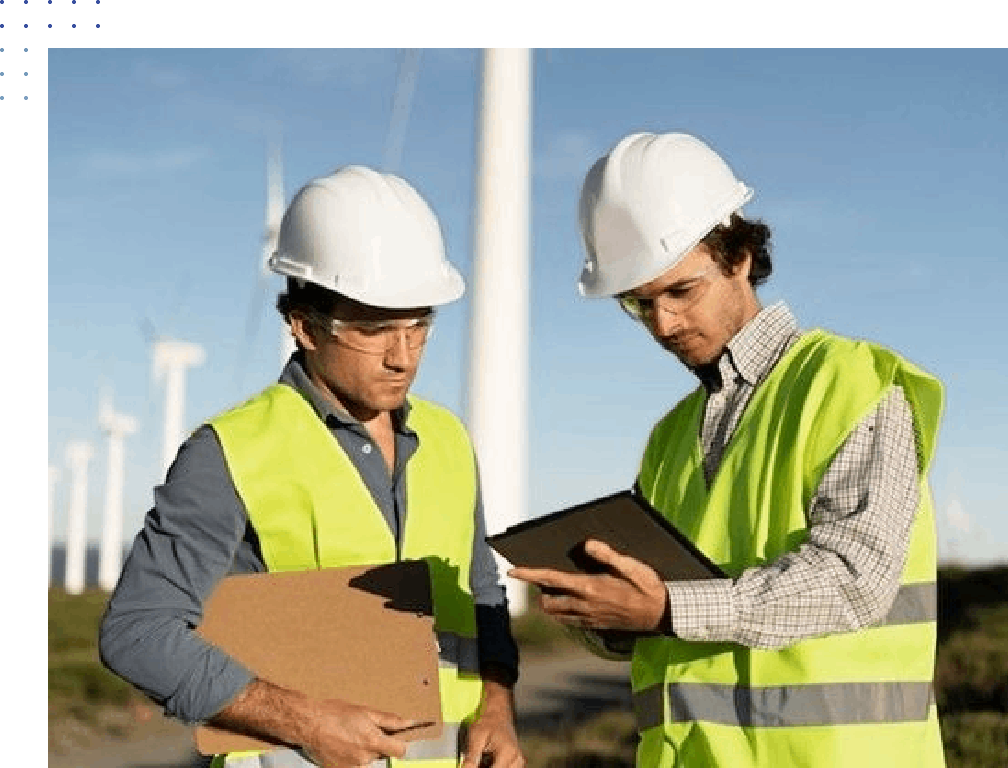 Two men in hard hats and vests looking at a tablet.